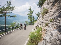 Levico See © Heiko Mandl Zwei Radfahrer fahren auf einer Bergstraße mit Blick auf See und Berge
