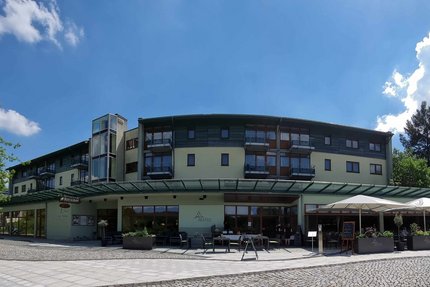 Hotel Am Kurhaus © Hotel Am Kurhaus Blick auf ein modernes Gebäude mit Außenbereich und Sonnenschirmen unter blauem Himmel
