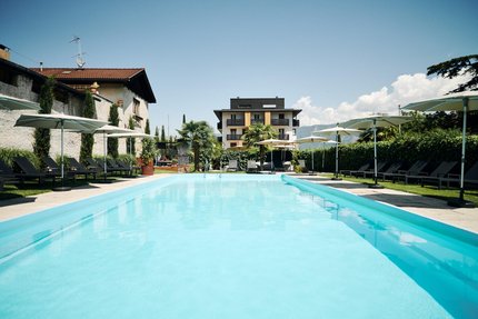 Traminerhof © Manuel Ferrigato Buitenzwembad met ligstoelen en parasols bij moderne gebouwen
