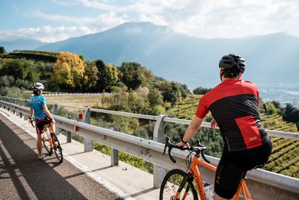 Malcesine Panoramica © Alex Moling Zwei Radfahrer mit Helmen auf Bergstraße mit Blick auf Tal und Berge
