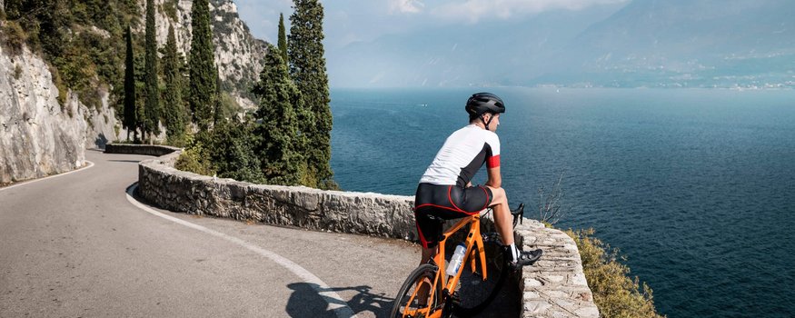 Rennrad Urlaub im Trentino © Alex Moling Radfahrer auf kurviger Straße mit Blick auf See und Berge