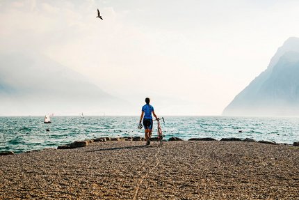 Monte Velo - Passo Santa Barbara © Alex Moling Fahrradfahrer am Seeufer mit Bergen und Segelbooten im Hintergrund