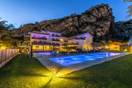 Triathlon & Rennrad Aktivhotel SantaLucia © Fabio Staropoli Beleuchtetes Hotel mit Außenpool vor Felsen bei Abenddämmerung