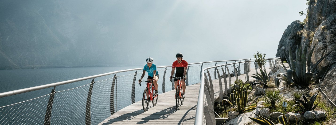 Rennrad Urlaub im Trentino © Alex Moling Zwei Radfahrer auf einem Steg am See mit Bergen im Hintergrund