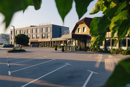 Hotel Grof © Ziga Intihar Hotelgebäude mit Parkplatz und grünen Blättern im Vordergrund