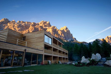Hotel Gran Paradiso © Davide dal Mas Modern houten gebouw met zonverlichte bergen en bos in het avondlicht