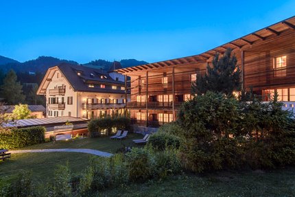 Hotel Ostaria Posta © Watzek Photografie Verlichte hotels met tuin en ligstoelen bij schemering in de bergen