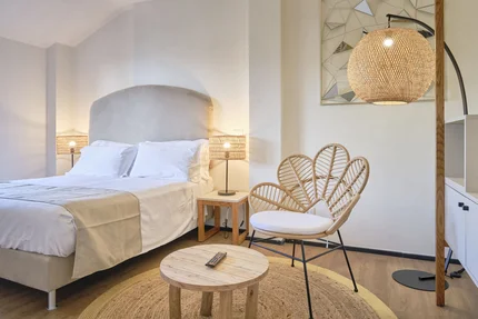 Villa Giada spEace & Bike Resort © Villa Giada spEace & Bike Resort Helles Schlafzimmer mit gemütlichem Bett, Rattanstuhl und warmem Licht