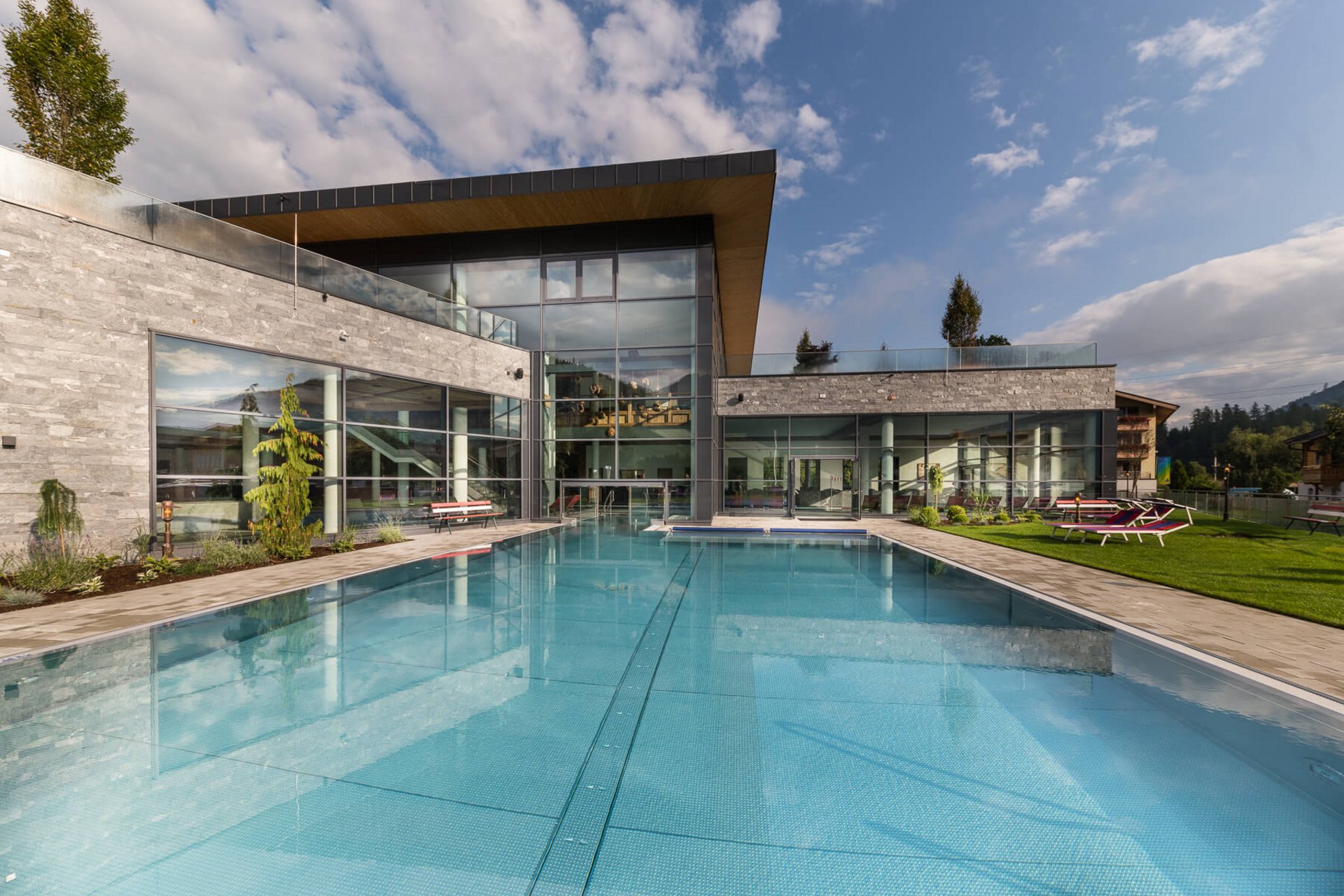 Roadbike Holidays © Klaus Bauer Moderner Außenpool mit Glasfassade und Liegestühlen an einem sonnigen Tag