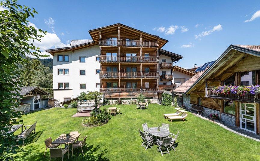 Sporthotel Exclusive **** © Sporthotel Exclusive SAS House with wooden balconies and garden with tables and loungers on sunny day