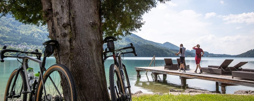 Rennrad Urlaub im SalzburgerLand © Erwin Haiden Zwei Fahrräder lehnen an einem Baum am See mit Steg und zwei Personen