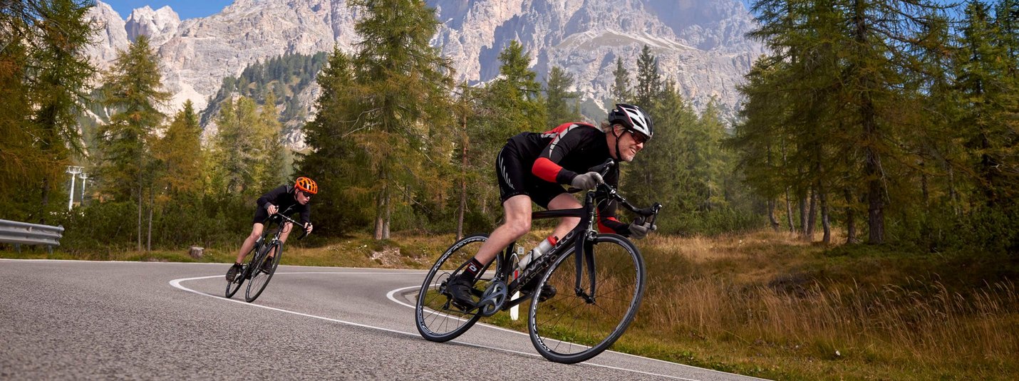 Antholz - Staller Sattel © Joris Lugtigheid Twee fietsers op een kronkelende bergweg met bomen en bergen op de achtergrond