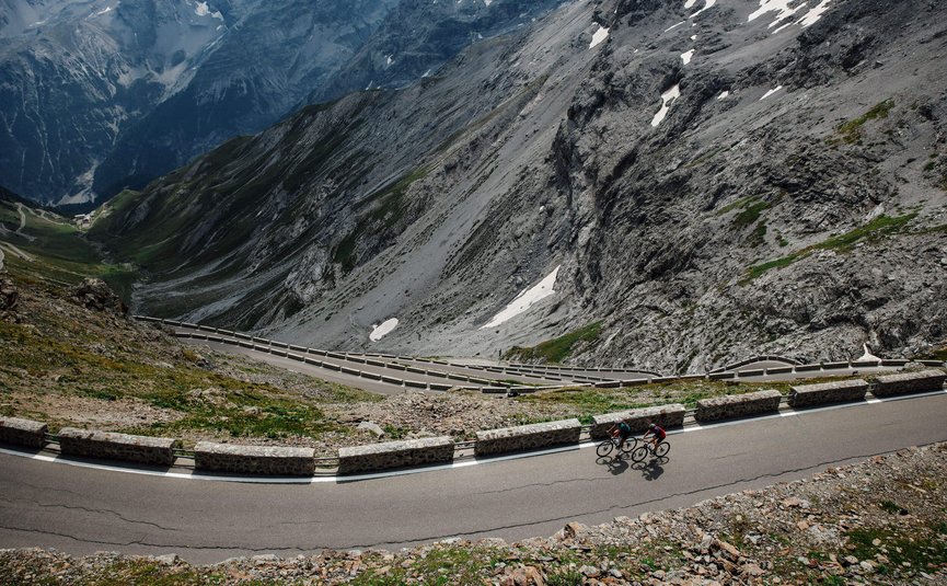 Vacanze in bici da corsa nella regione di Nauders – Lago di Resia © Felix Saller Due ciclisti su strada di montagna tortuosa con ripide scogliere rocciose