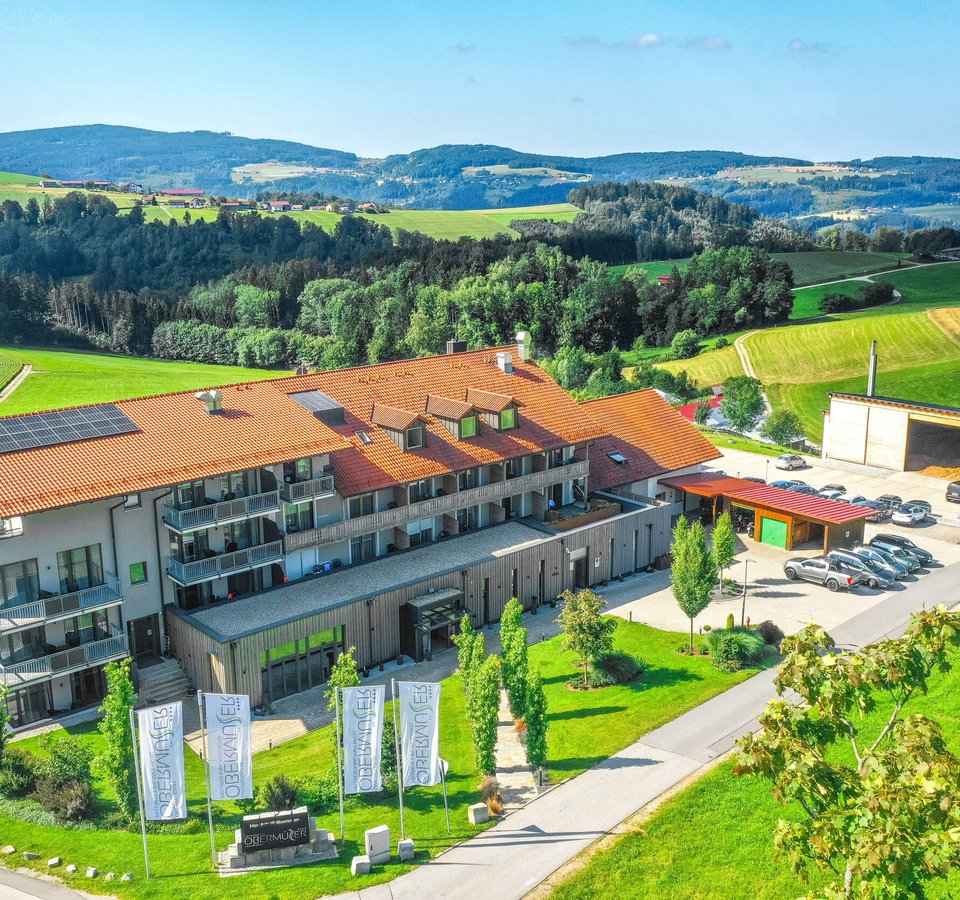 Landrefugium Obermüller – aktiver Rückzug im Rennradrefugium
© Stefan J. Wolf Photography Modernes Gebäude mit rotem Dach und Autos in grüner Hügellandschaft
