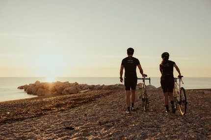 Marken © Alex Moling Zwei Radfahrer bei Sonnenuntergang am Strand mit Blick aufs Meer