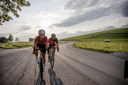Tirol © Felix Saller Zwei Radfahrer fahren auf einer Landstraße bei Sonnenuntergang
