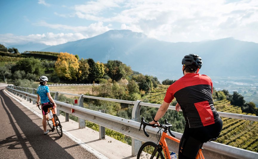 Racefietsvakantie aan het noordelijke Gardameer © Alex Moling Twee wielrenners met helmen op bergweg met uitzicht op vallei en bergen