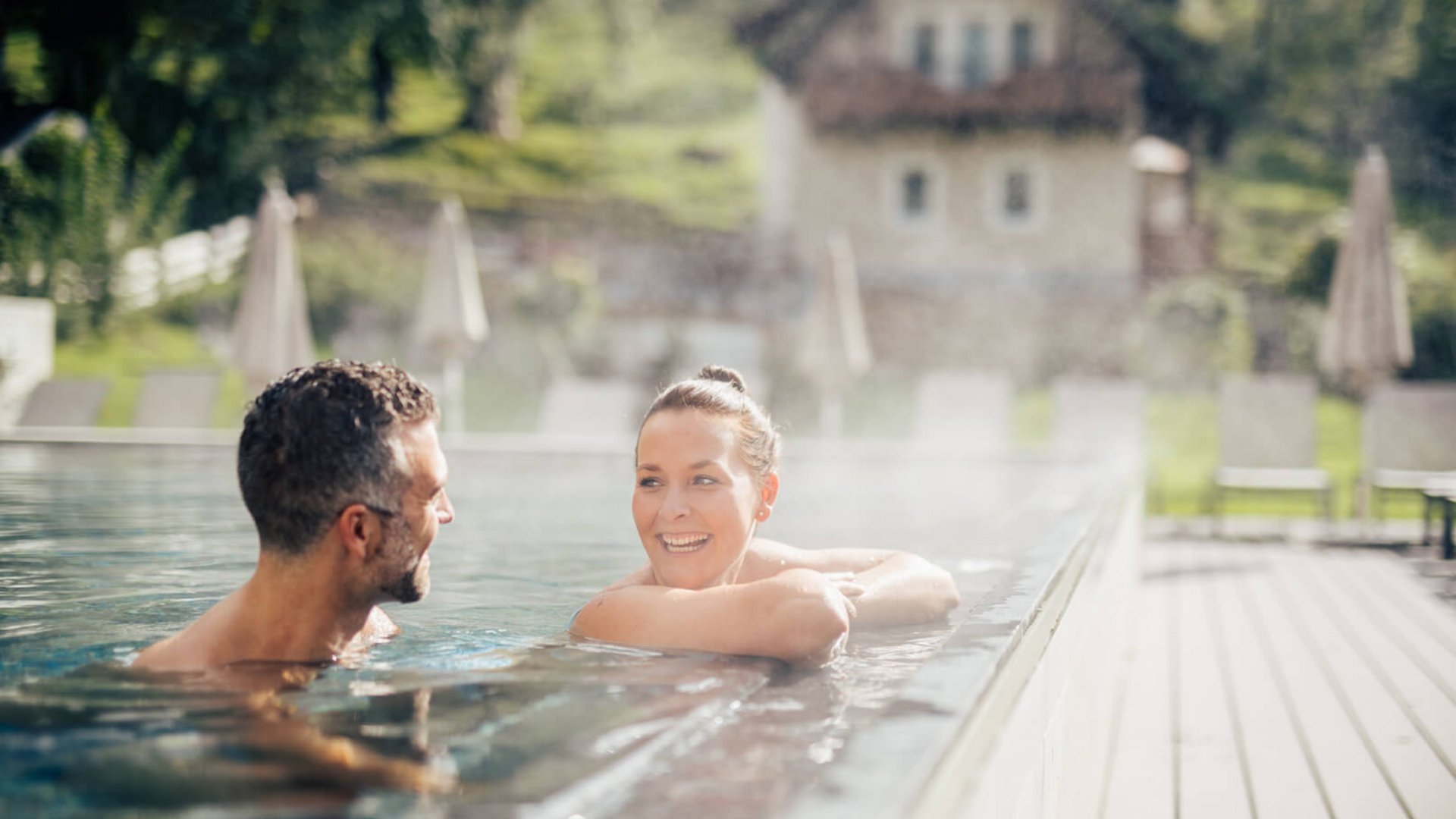 Roadbike Holidays © Daniel Waschnig Paar entspannt im warmen Außenpool an einem sonnigen Tag