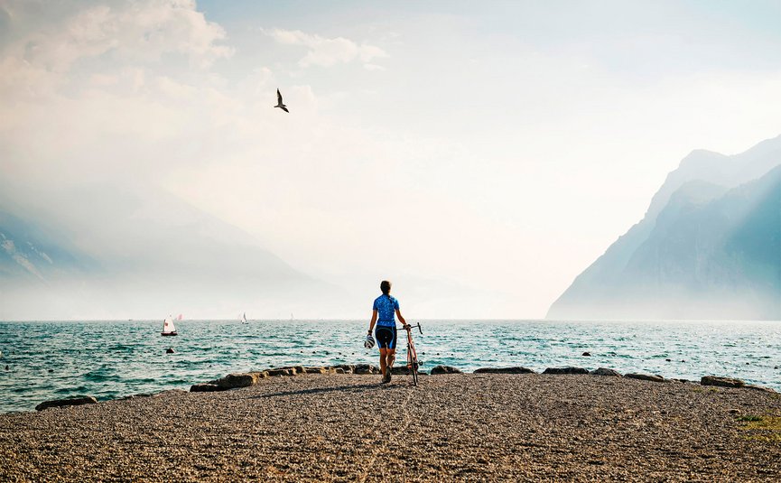 Racefietsvakantie aan het noordelijke Gardameer © Alex Moling Fietser aan het meer met bergen en zeilboten op de achtergrond