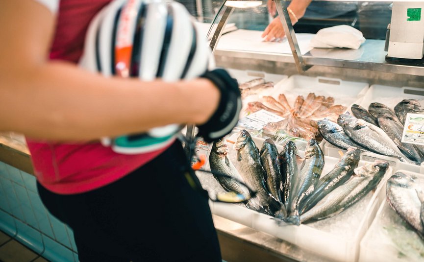 Road bike holidays on the Adriatic coast © Alex Moling Person holding bicycle helmet in front of fresh fish display at market