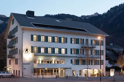Hotel Bären & Cafe Deli © Hotel Bären - Cafe Deli Mellau Beleuchtetes Hotelgebäude mit Bergen im Hintergrund bei Dämmerung