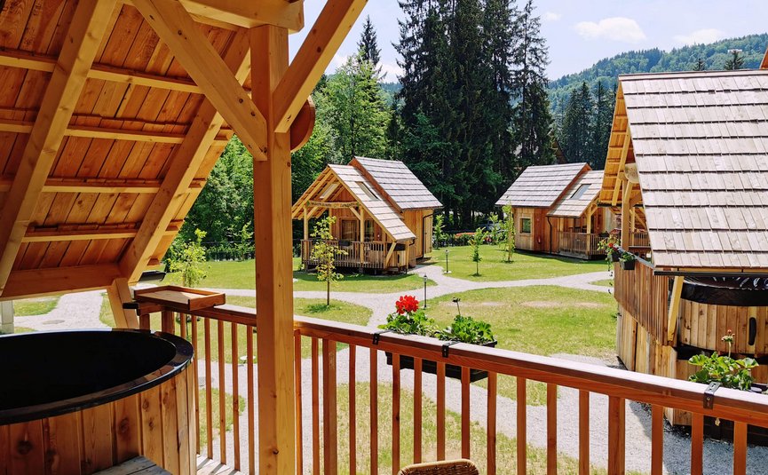 Hotel & Glamping Ribno Alpine Resort **** © Katarina Strgar Blick von Holzveranda auf kleine Holzhäuser und Wald im Hintergrund