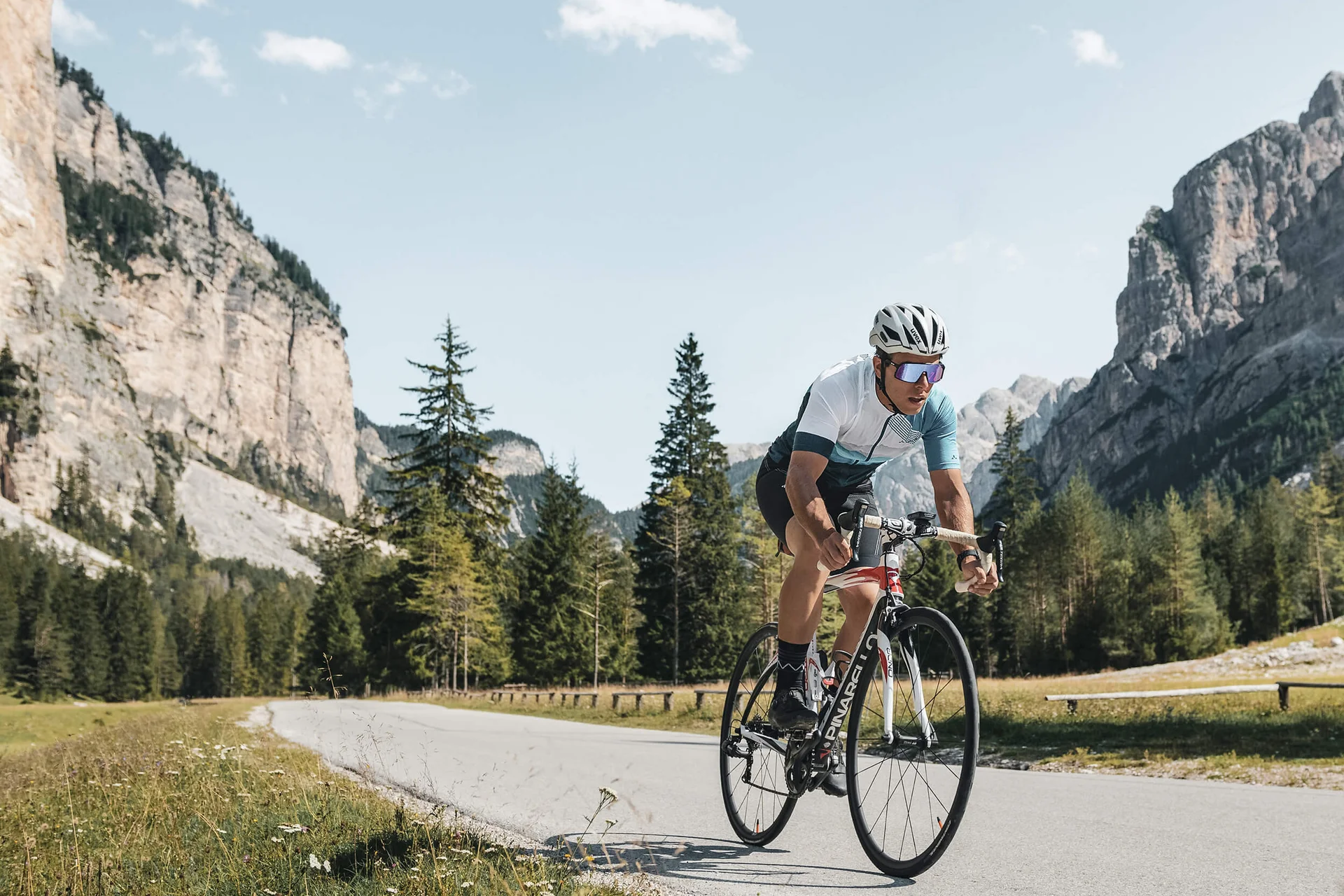 Roadbike Holidays © Alex Moling Fahrradfahrer fährt auf Bergstraße mit Felsen und Bäumen im Hintergrund