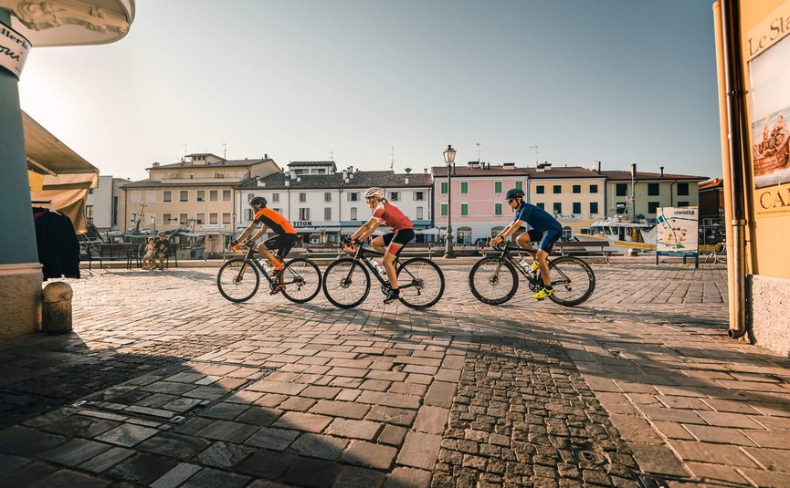 Road bike holidays on the Adriatic coast © Alex Moling Three cyclists riding through a sunny square in a small town