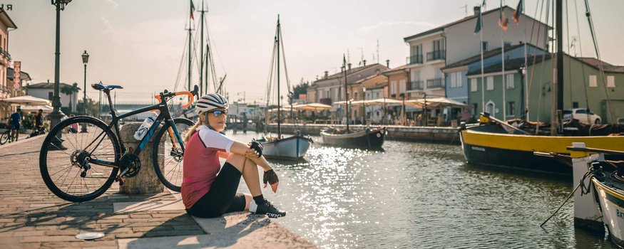 Adriatic coast © Alex Moling Cyclist sitting by the harbor with boats and bike in the sunlight