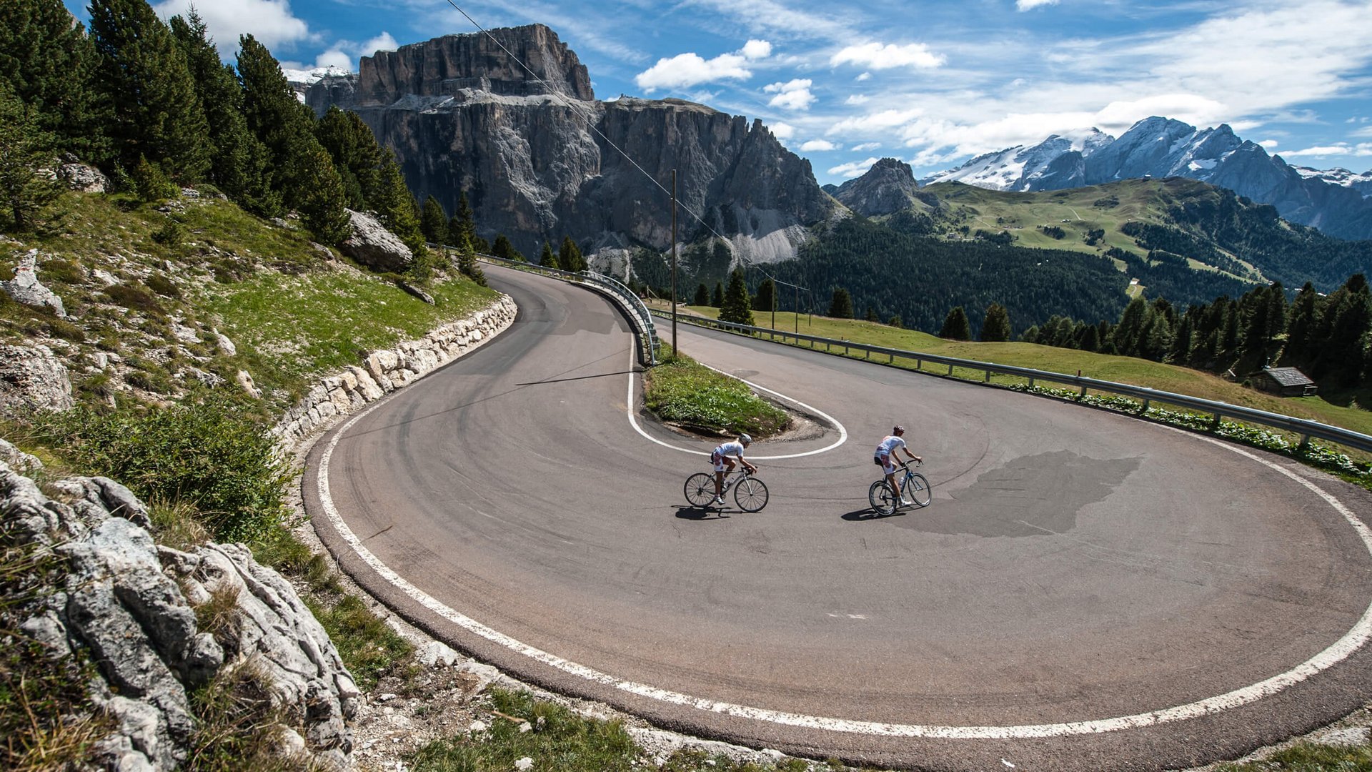 Tours & Travels © Paola Finali Cyclists riding sharp hairpin bend on mountain road with scenic views