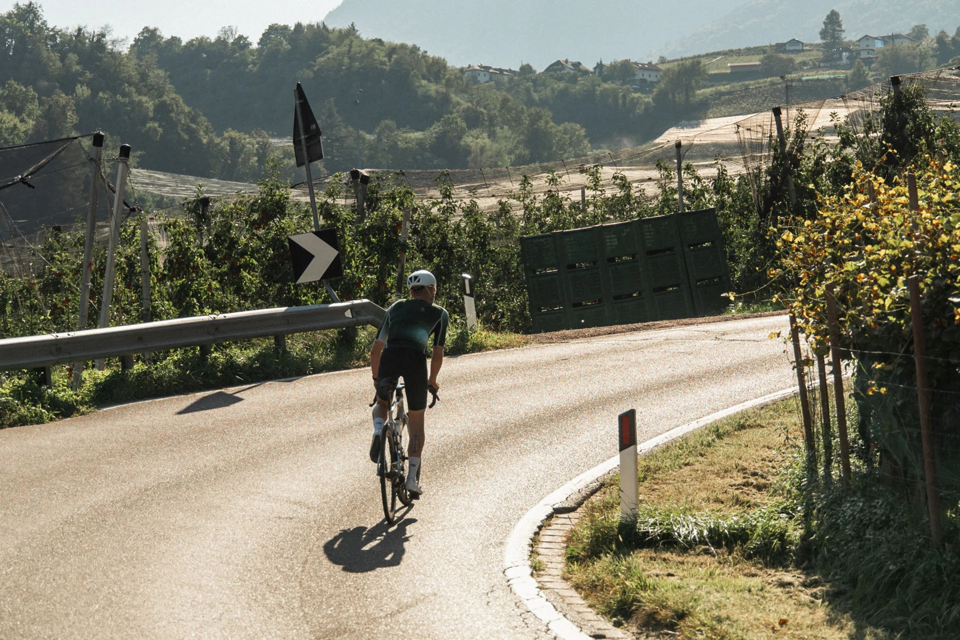 Roadbike Holidays © marc.moves x velysiped Radfahrer auf einer kurvigen Landstraße mit Bergen im Hintergrund