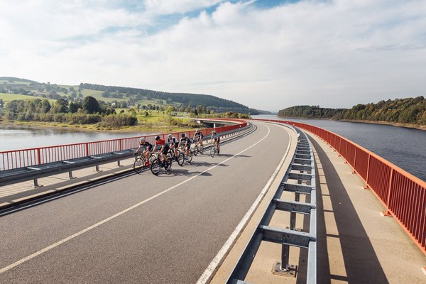 Deutschland © Felix Meyer Gruppe von Radfahrern fährt über Brücke neben Fluss und grüner Landschaft