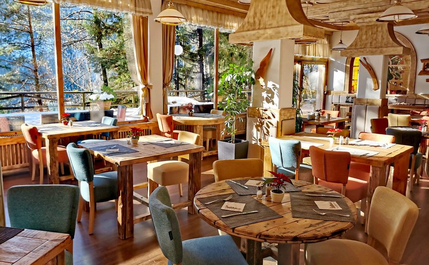 Hotel & Glamping Ribno Alpine Resort **** © Katarina Strgar Gemütliches Restaurant mit Holztischen und bunten Stühlen, hellem Tageslicht