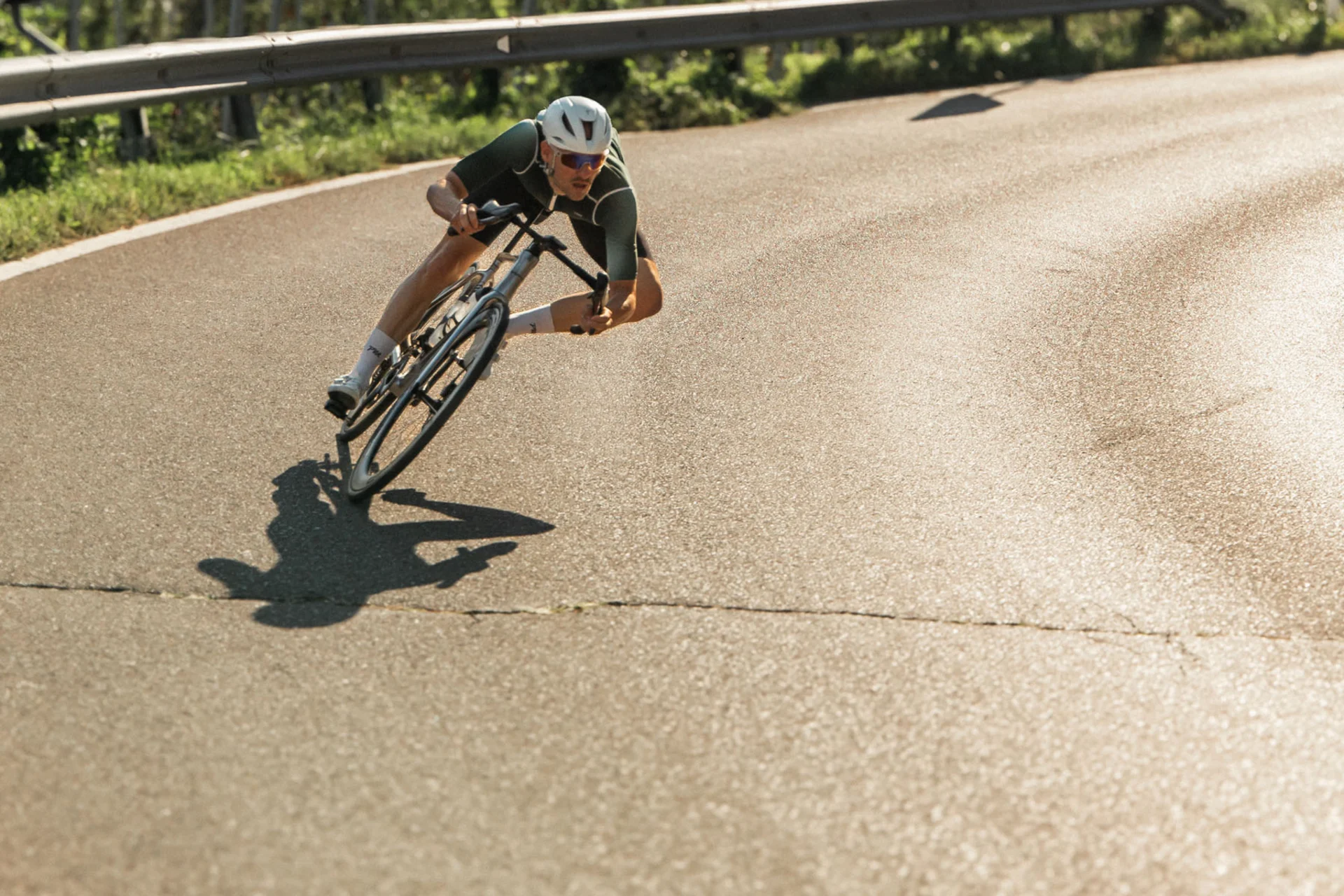 Roadbike Holidays © marc.moves x velysiped Fahrradfahrer mit Helm fährt schnell um eine Kurve auf Bergstraße