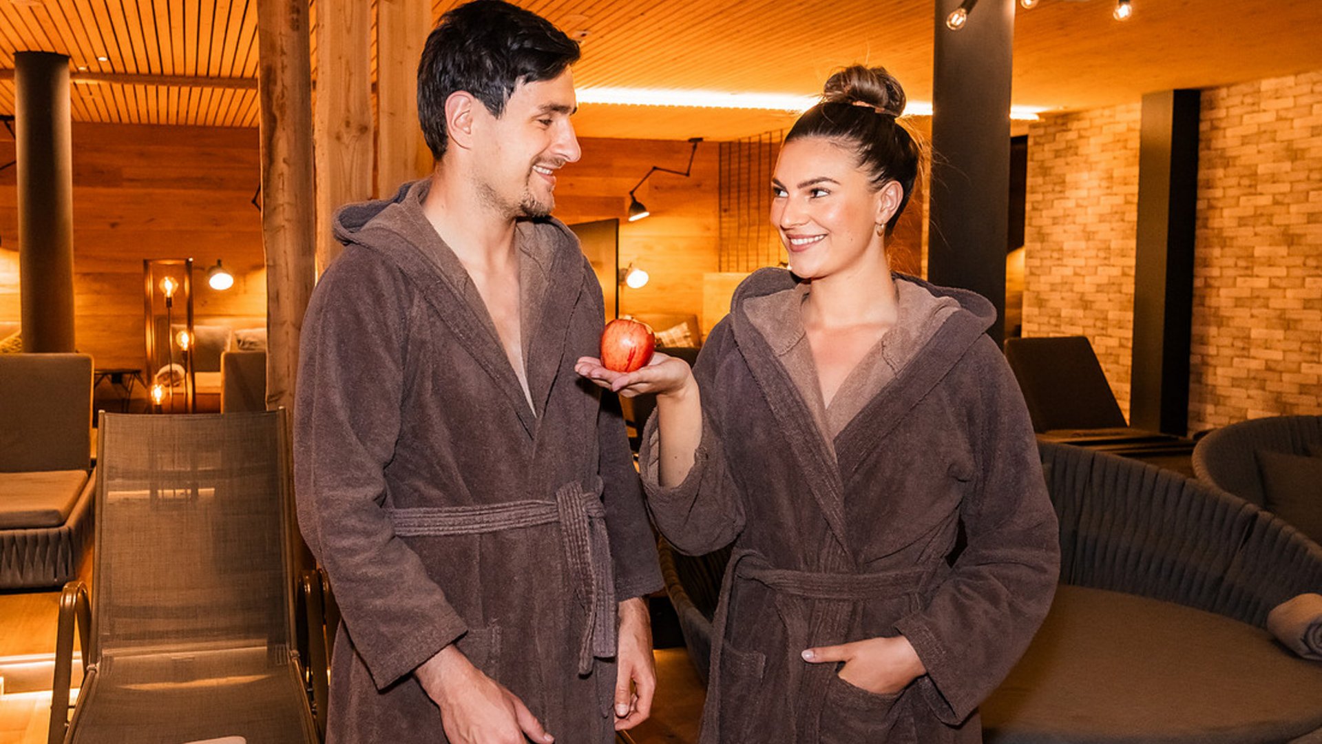 Landrefugium Obermüller – aktiver Rückzug im Rennradrefugium
© Stefan J. Wolf Photography Paar in Bademänteln im Spa, Frau hält einen Apfel