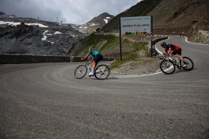 Roadbike Holidays © Felix Saller Zwei Radfahrer auf einer Bergstraße nahe einem Südtirol-Schild