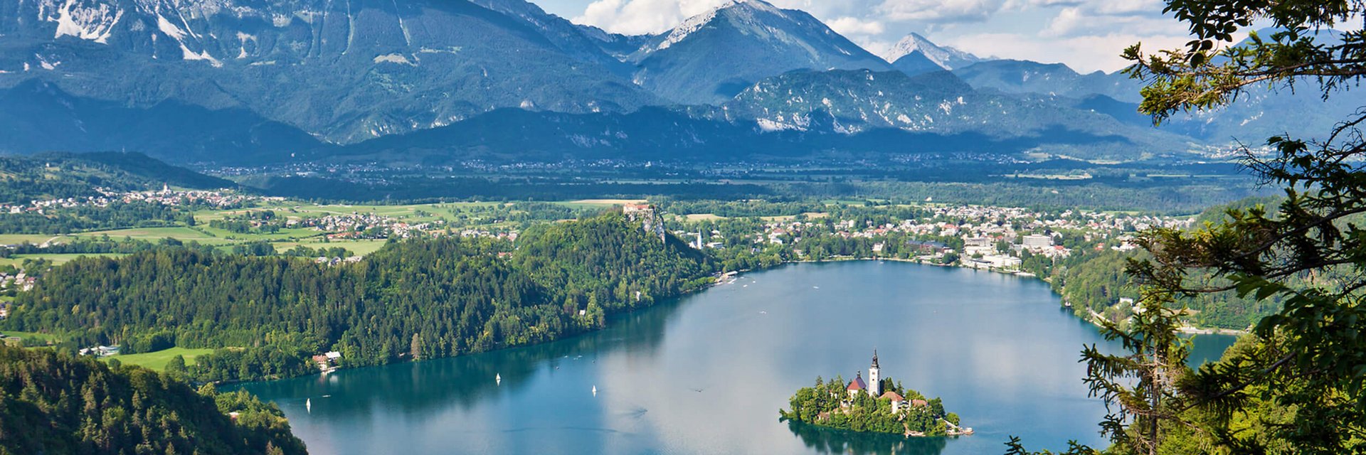 Hotel & Glamping Ribno Alpine Resort **** © www.slovenia.info - Jost Gantar See mit Insel und Kirche, umgeben von Wald und Bergen im Hintergrund