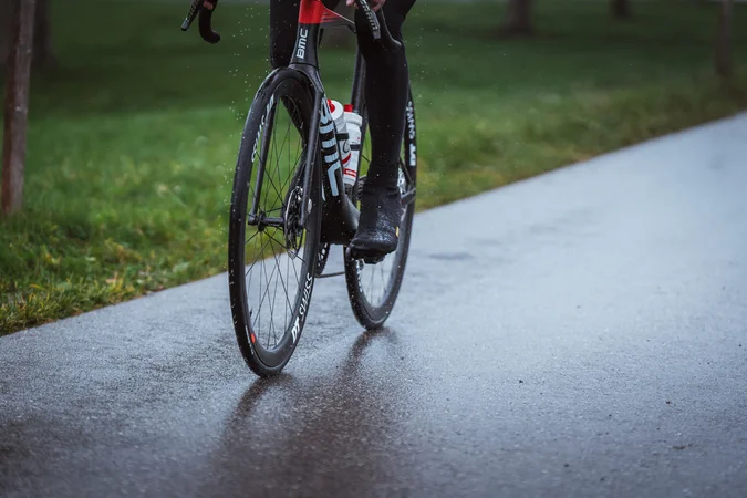 Roadbike Holidays © Ralf Bohle GmbH Nahaufnahme eines Radfahrers auf einem Rennrad auf nasser Straße