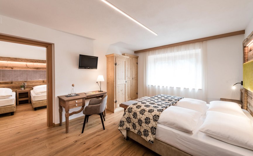 Sporthotel Exclusive **** © Sporthotel Exclusive SAS Bright hotel rooms with double and single beds, wooden furniture, and modern decor