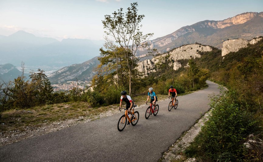 Racefietsvakantie aan het noordelijke Gardameer © Alex Moling Drie fietsers op bergweg met rotsachtige heuvels op de achtergrond