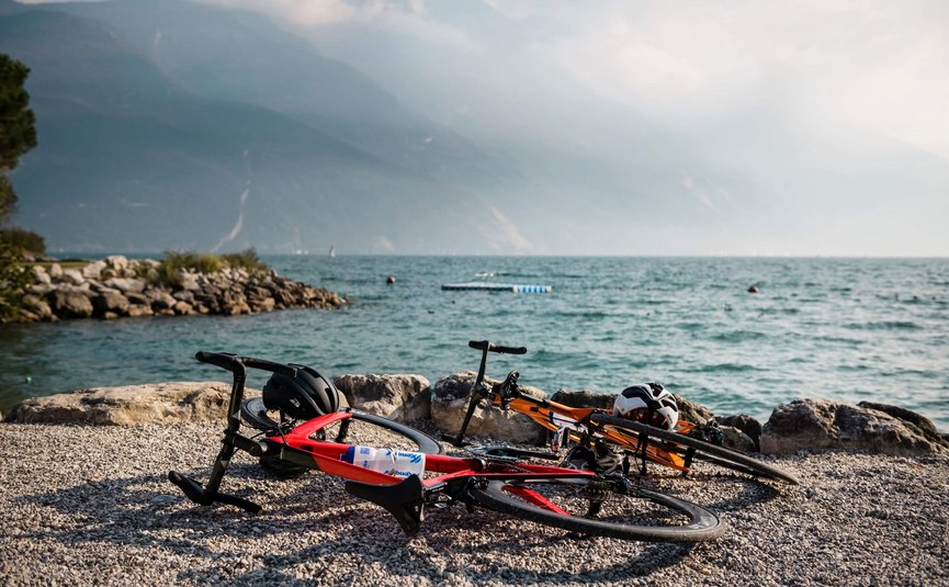 Racefietsvakantie aan het noordelijke Gardameer © Alex Moling Twee racefietsen liggen aan een meerkust met bergen op de achtergrond