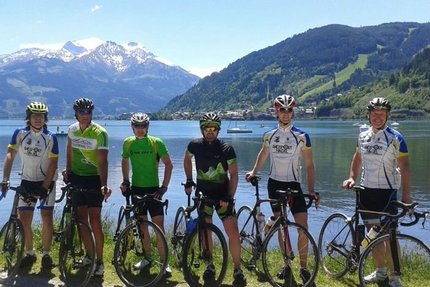 Dientenrunde © Sportcamp Woferlgut Bruck Sechs Radfahrer mit Rennrädern vor einem Bergsee und schneebedeckten Bergen