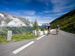 Pinzgau © Heiko Mandl Zwei Radfahrer fahren auf einer Bergstraße mit Bergen und blauem Himmel im Hintergrund