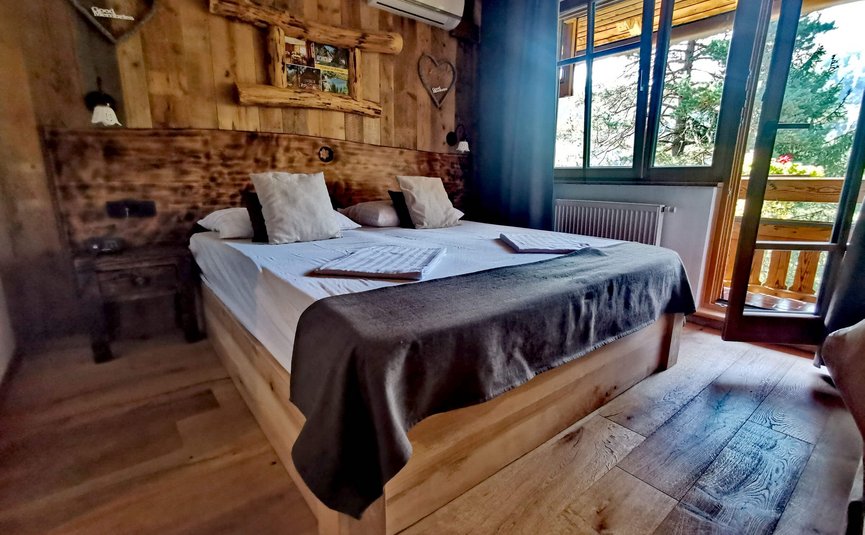 Hotel & Glamping Ribno Alpine Resort **** © Katarina Strgar Gemütliches Holzschlafzimmer mit Doppelbett und Balkonblick