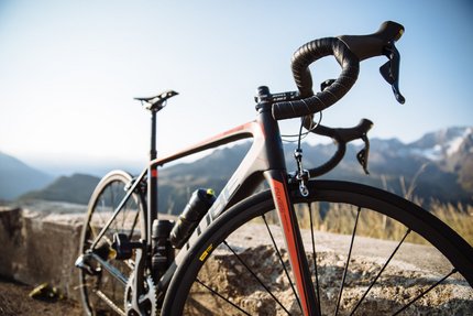 Rennrad Ausrüstung: Dein Guide für den perfekten Start © Benjamin Pfitscher Sportliches Rennrad vor Berglandschaft auf sonnigem Tag