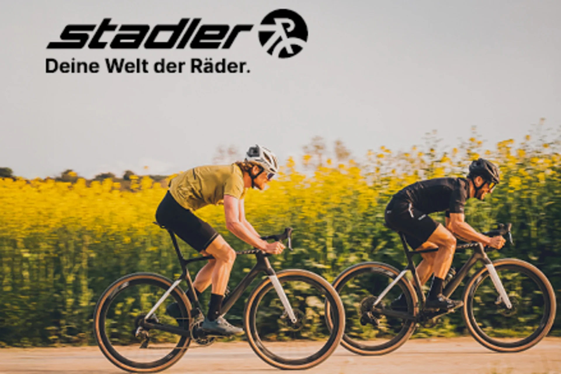Roadbike Holidays © Scott by JAF Zwei Radfahrer fahren auf einem Weg vor einem Feld mit gelben Blumen