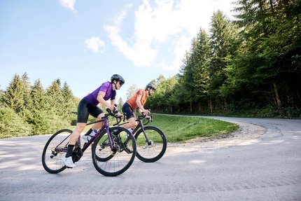 Rennradfahren im Land der Champions: Slowenien © Tobias Köhler Zwei Radfahrer auf der Straße in einer bergigen Waldlandschaft.